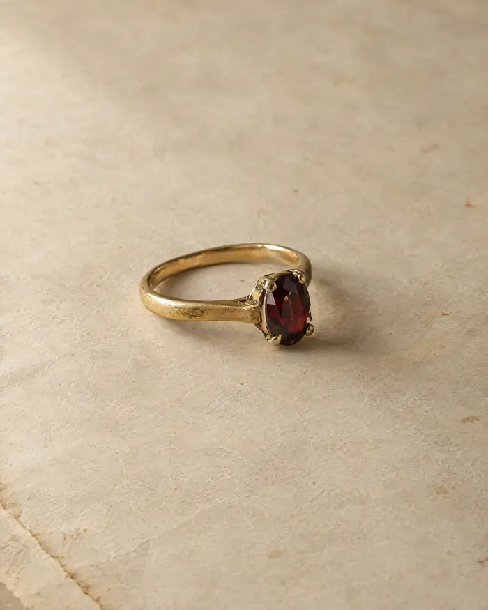 An older yellow-gold ring with a small garnet on aged paper